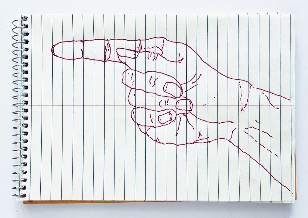 An outline handsketch of a hand shaping the ASL American manual letter “G”, in red ink on a yellow spiral bound steno notebook. 