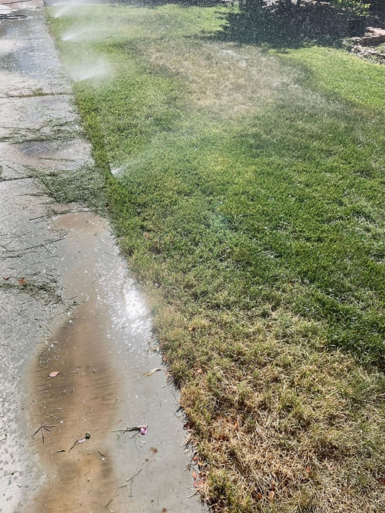 A mown lawn with sprinklers running to partially salve the devastation.